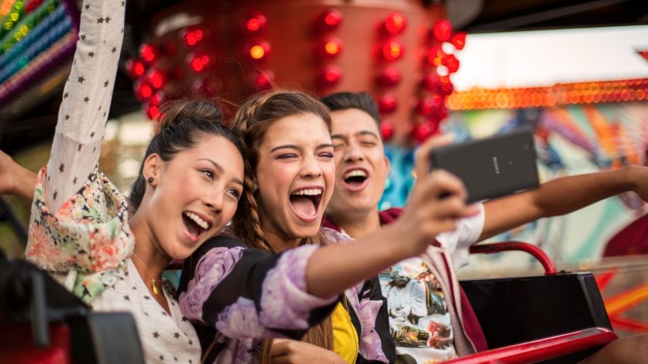 A group of friends on a fairground ride using the Xperia C4 to take a selfie