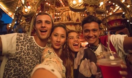 Selfie shot of a group of friends at a fairground taken in low light