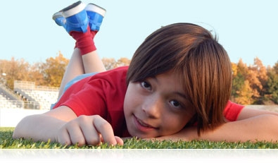 Photo of a boy lying on the grass on a soccer field, looking at the camera