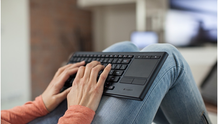 Person holding K830 keyboard in living room setting