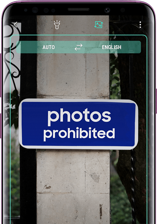Galaxy S9+ displaying a translated sign with the untranslated sign in the background