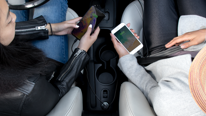 Two people charging their smartphones in the car
