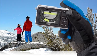 Focus on the shot with the Nikon 1 AW1 Photo of the Nikon 1 AW1 in a gloved hand with a parent and child in the background on a mountain