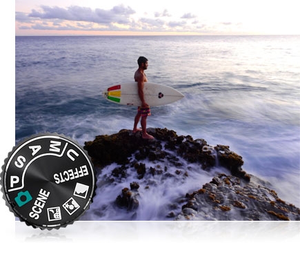 COOLPIX P900 photo of a surfer on the jetties at the water's edge and the mode dial inset